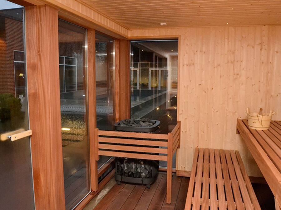 Una sauna con bancos de madera, una puerta de vidrio y vistas al exterior.