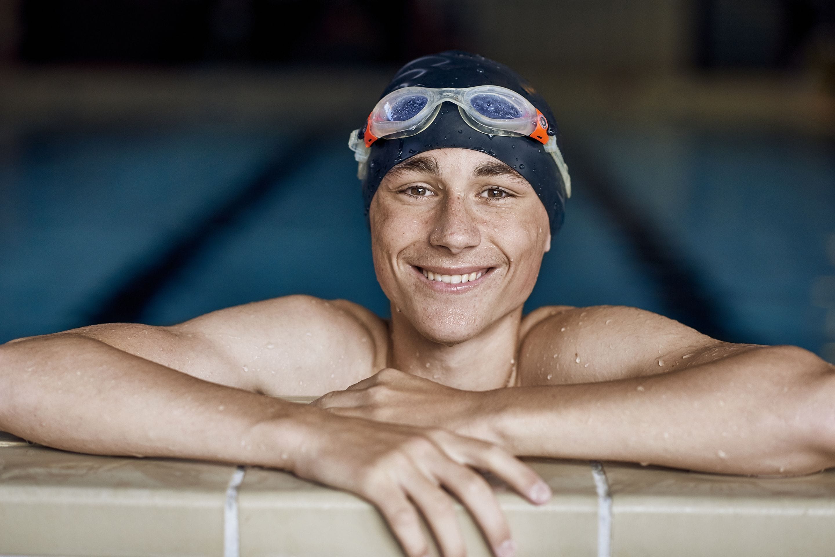 A person leaning on a pool edge with a blurred background.