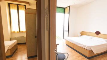 Une chambre d’hôtel avec un lit, une chaise, un bureau et une fenêtre avec des rideaux.