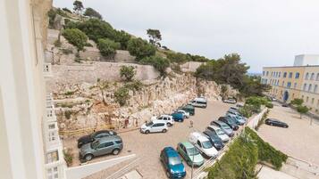 Un aparcamiento con varios coches, un muro de piedra y un edificio con una puerta azul.