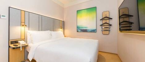 Une chambre d’hôtel comprenant un lit, une table de chevet, une lampe, une œuvre d’art et un miroir.