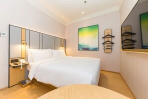 A hotel room with a bed, bedside table, lamp, artwork, and a mirror. - Ji Hotel- Shanghai Bund Ningbo Road Branch (Shanghai)