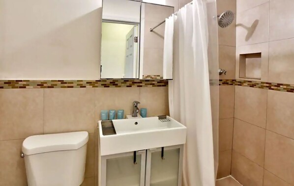Une salle de bain avec des toilettes, un lavabo et une douche.
