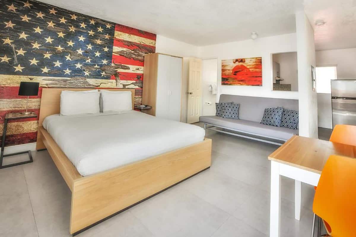 Una camera d'albergo moderna con un letto grande, un divano, un tavolino e un frigorifero.