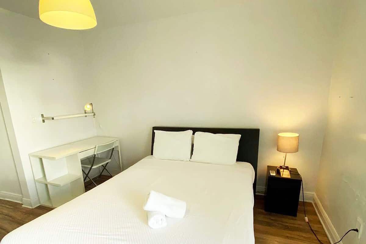 Una camera da letto ordinata con un letto, una scrivania e una sedia.