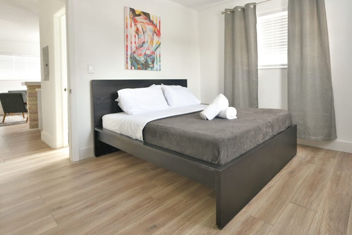 Una camera da letto moderna con un letto, un quadro e vista sull'esterno.