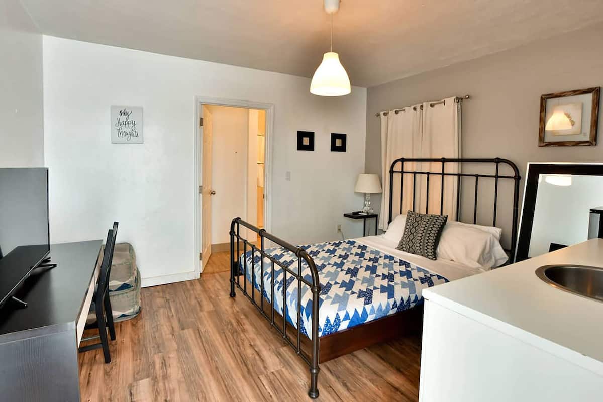 Una camera da letto con un letto, un comodino, una lampada e una scrivania con una sedia.