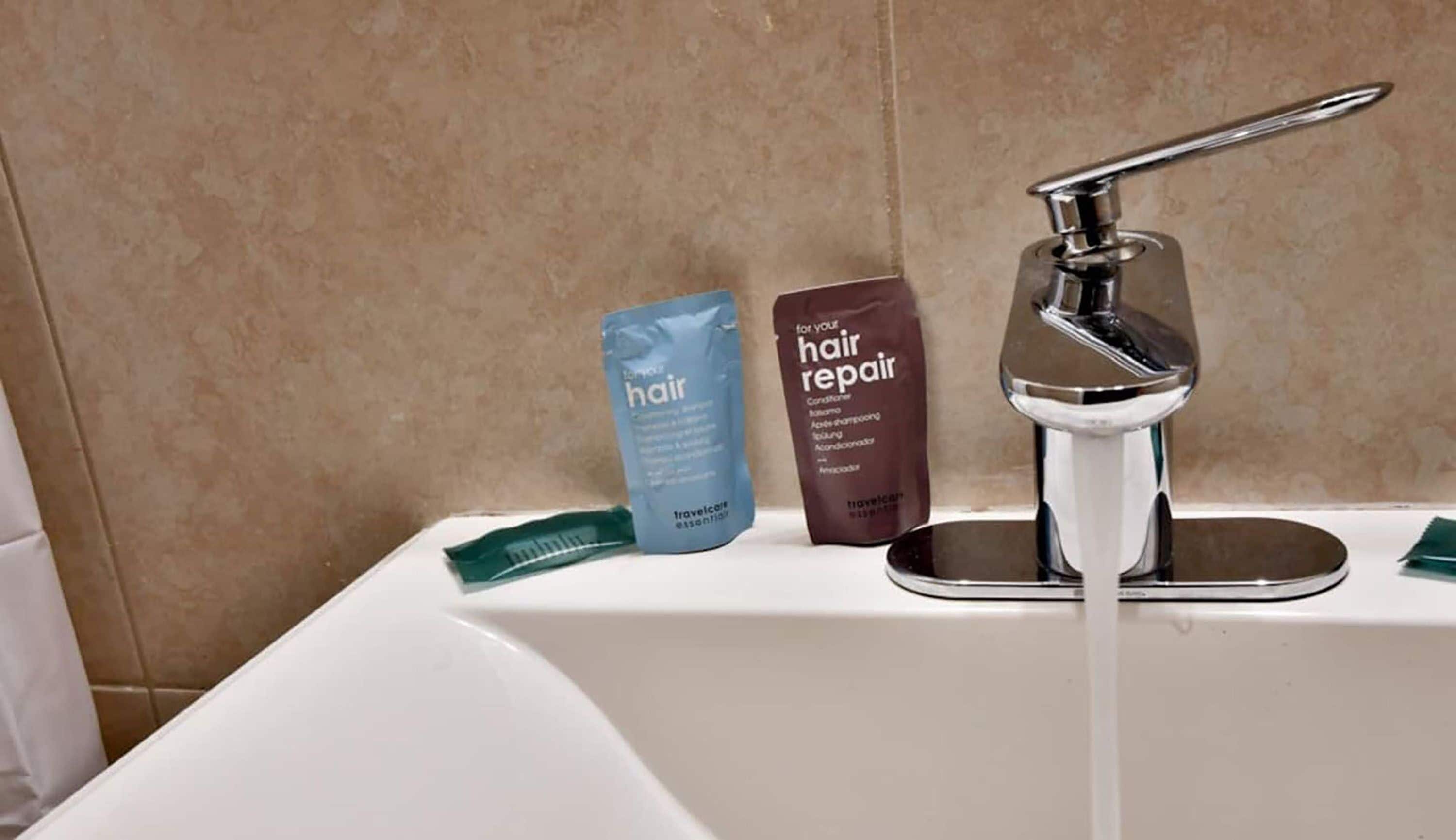 A bathroom sink with toiletries including a blue bottle labeled "hair" and a brown bottle labeled "hair repair".
