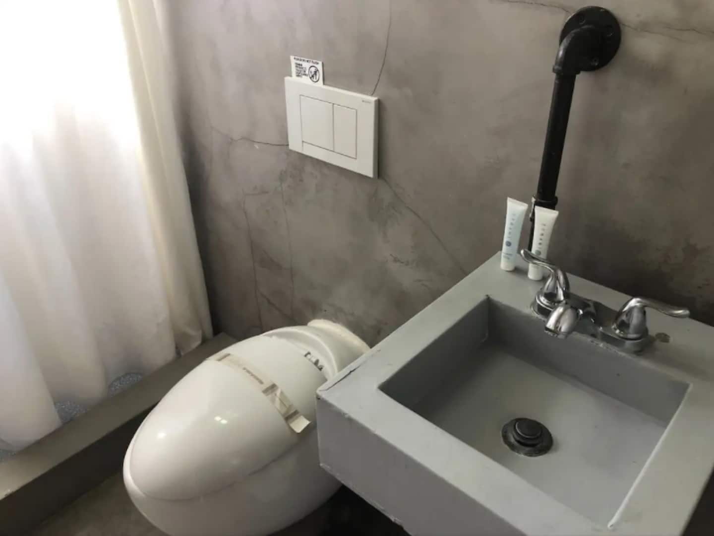 A bathroom with a white toilet, a grey sink, and a towel rack.