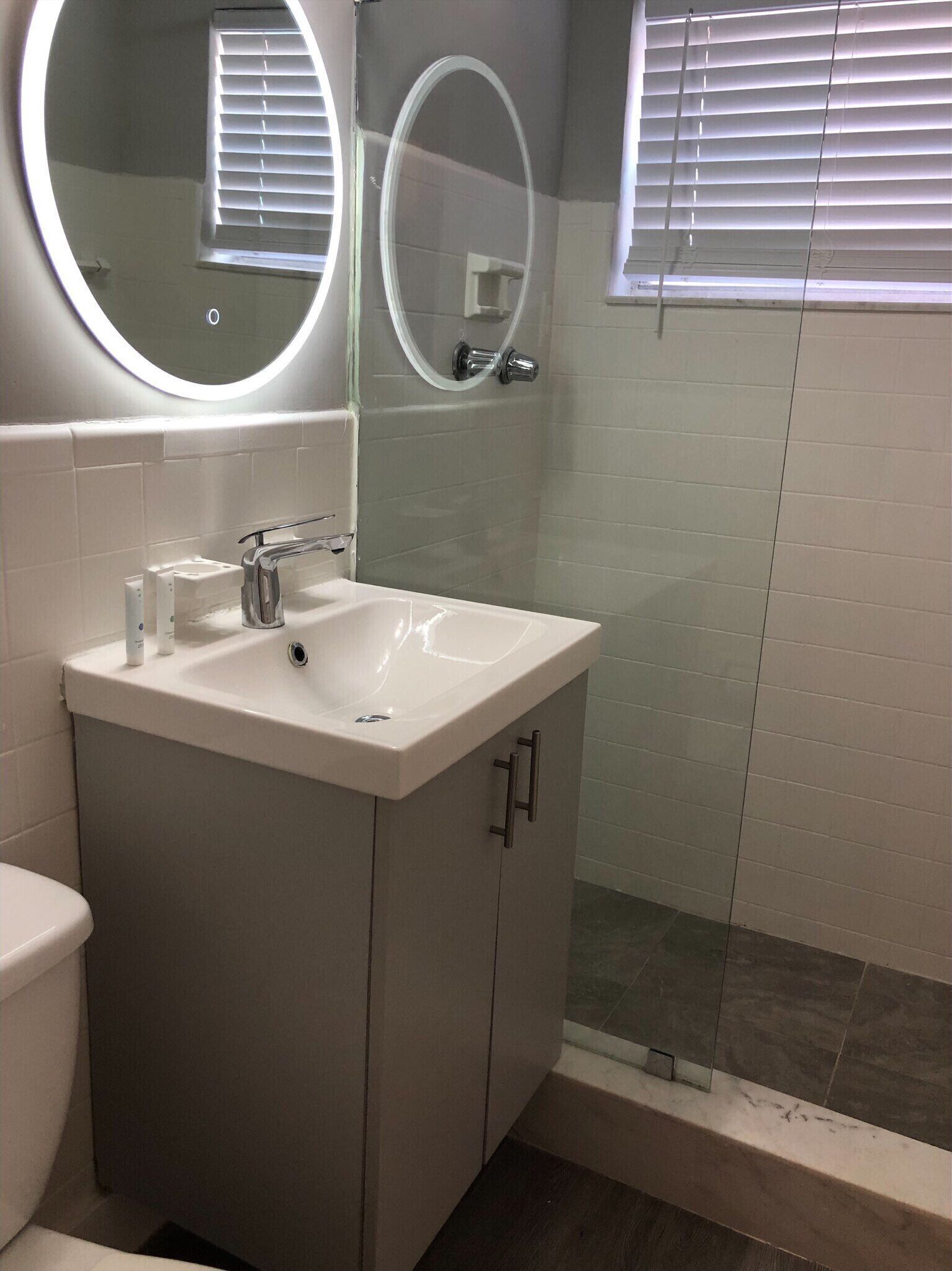 A bathroom with a white sink, a mirror, and a shower.