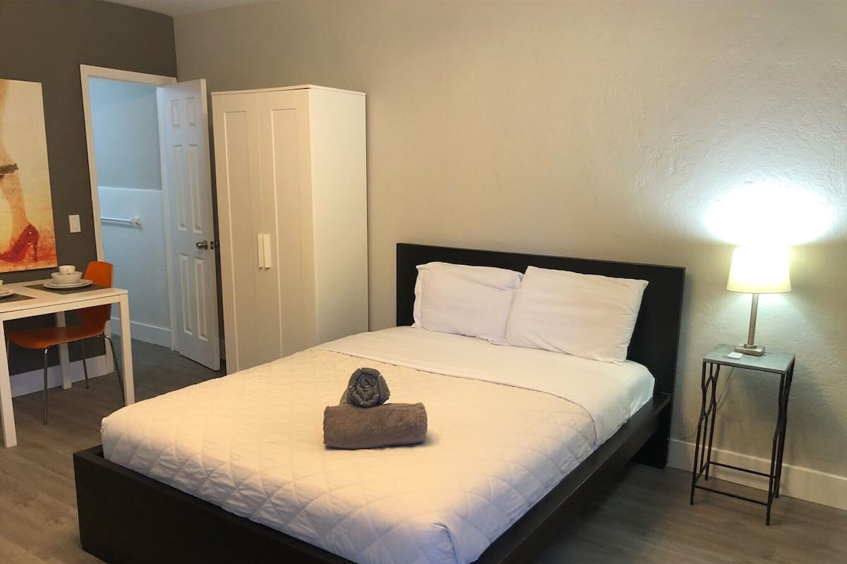 Una camera d'albergo ordinata con un letto, una scrivania e una sedia.