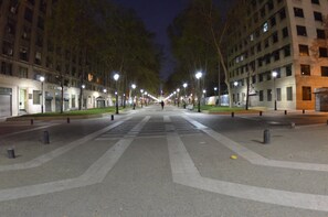 A wide, tree-lined street at night with evenly spaced street lamps and buildings on either side.