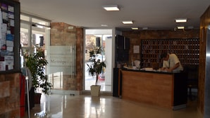 A reception area with a wooden reception desk, a potted plant, and a glass door leading to the outside.