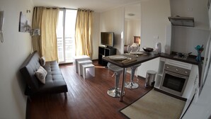 A modern kitchen with a dining area, a sofa, and a TV.