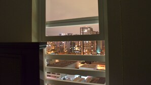 A view of a cityscape through a window with multiple floors of buildings, some with illuminated windows.