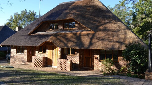 A thatched-roof house with a brick lower level and a wooden upper level. - Kruger Park Lodge - Golf Safari SA (Mbombela)
