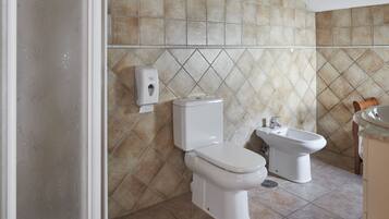 A bathroom with a toilet, bidet, and hand dryer.