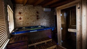 A wooden spa area with a hot tub, stone wall, and wooden door. - Country House Le Vedute (Trevi)