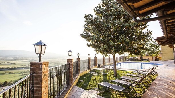 A poolside area with a view of the countryside, a tree, and a pergola structure. - Country House Le Vedute (Trevi)