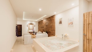 A modern bathroom with a large bathtub, a wooden accent wall, and a small seating area with a table and chairs. - Alam Penari Ubud (Ubud)