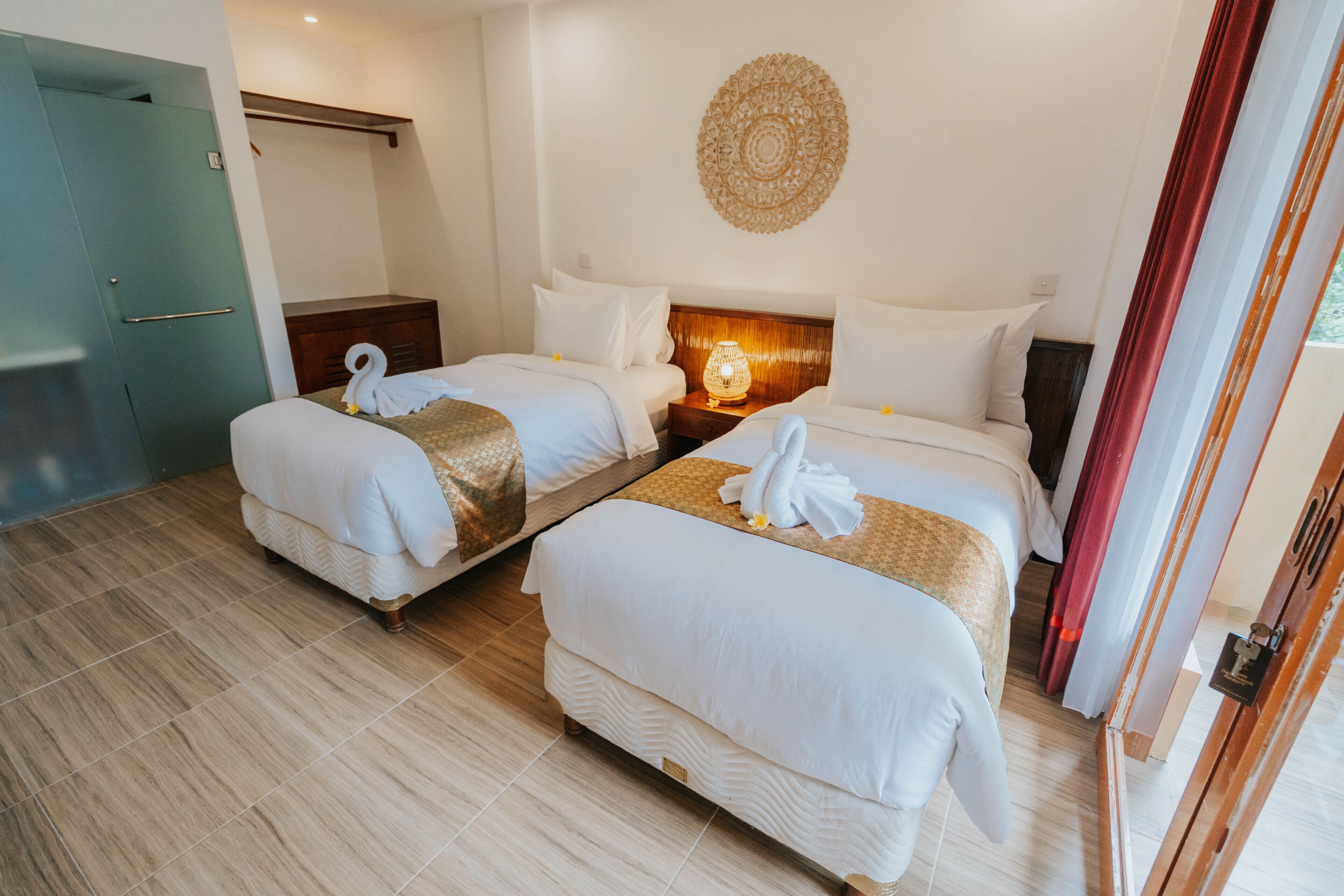 Une chambre d’hôtel avec deux lits, une tête de lit en bois, une décoration murale et une porte.
