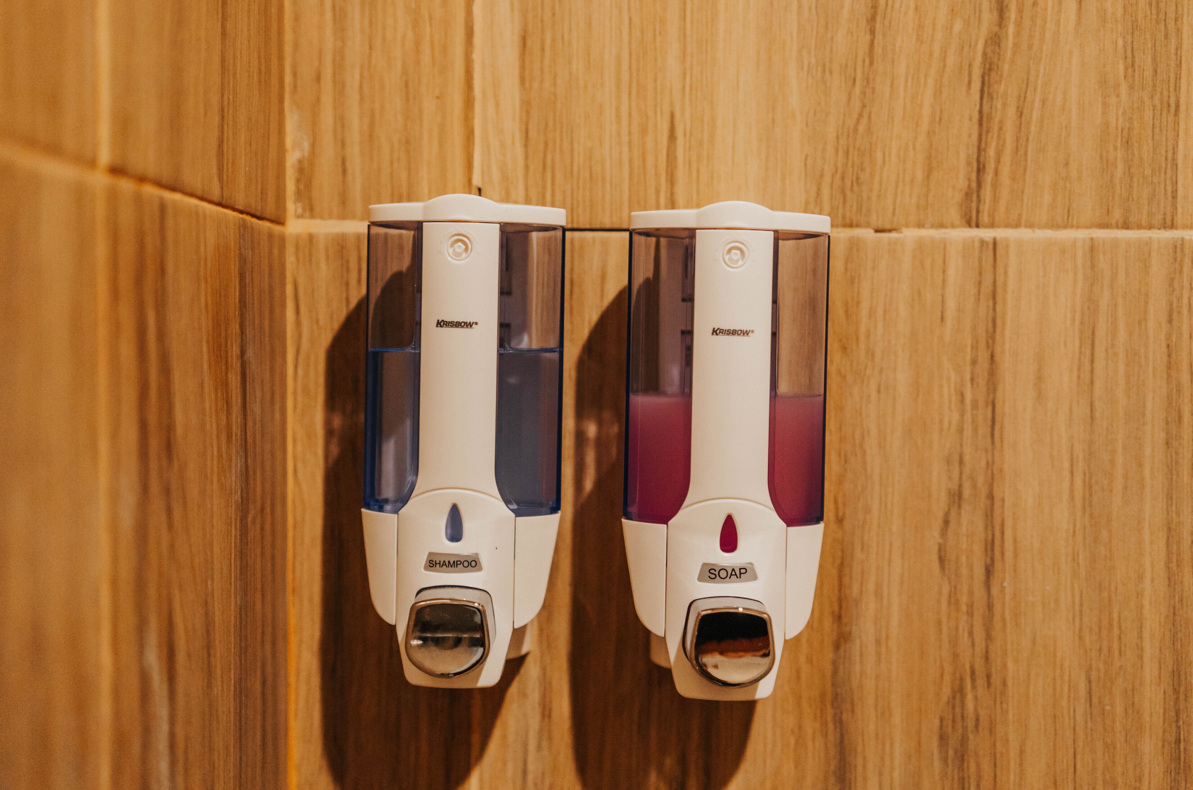 Dos dispensadores de jabón para manos montados en una pared de madera.