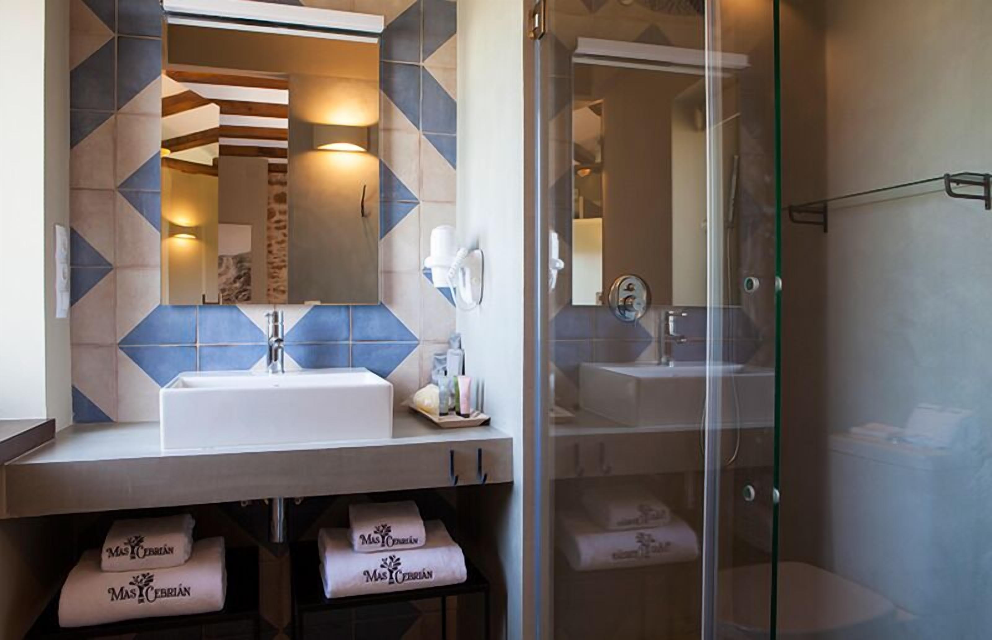 Un baño con un espejo grande, dos lavamanos y una cabina de ducha de vidrio.