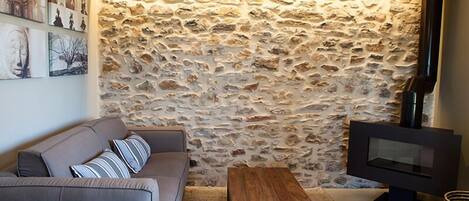 A living room with a stone wall, a sofa, a wooden coffee table, and a flat-screen TV.