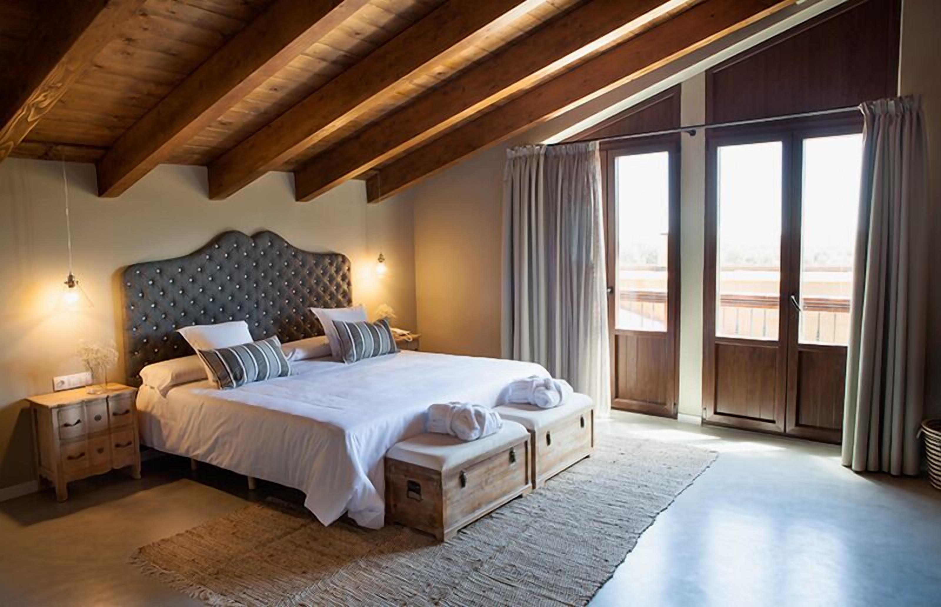 A bedroom with a large bed, wooden headboard, bedside tables, and a view through a sliding door.