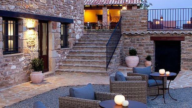 A stone building with outdoor seating and a staircase leading to an upper level. - Hotel Mas de Cebrián (Puertomingalvo)