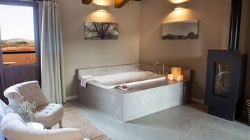 A modern bathroom with a large bathtub, a wooden ceiling, and a view of the outdoors.