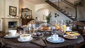 A breakfast setting with a table set for four, including plates, bowls, glasses, and a variety of breakfast items. - Dimora Torremuzza (Palermo)