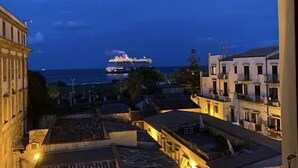A view of a coastal town at dusk with a cruise ship in the distance. - Dimora Torremuzza (Palermo)