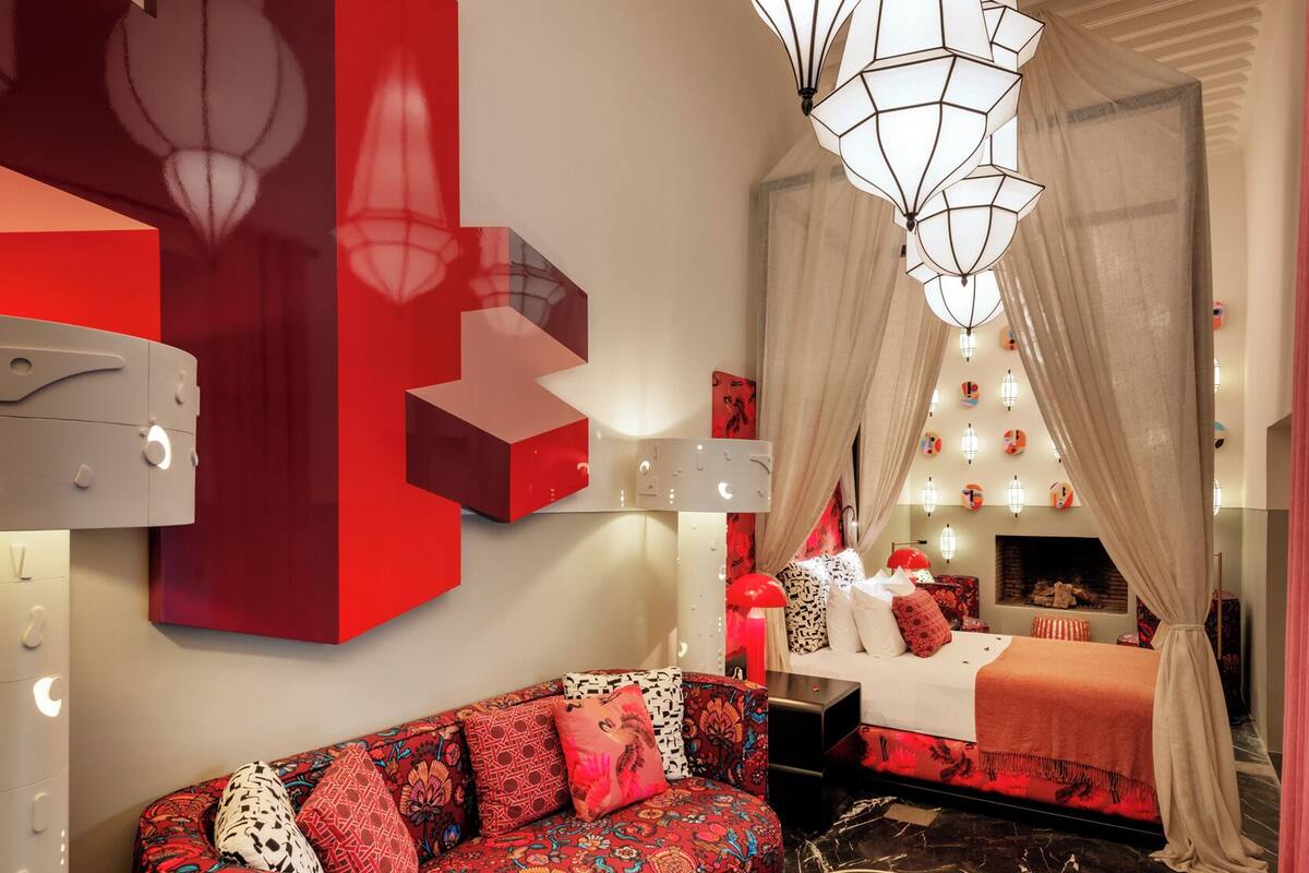 A modern bedroom with a red and white color scheme, a large bed, a red sofa, and a unique circular coffee table.