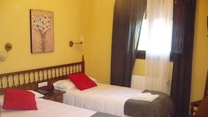 A hotel room with two beds, a painting on the wall, a lamp, and a window with curtains. - Hotel Castillo de Uña (Una)