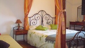 A bedroom with a four-poster bed, a bedside table with a lamp, and a television on a stand. - Hotel Castillo de Uña (Una)