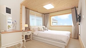 Ein Schlafzimmer mit Bett, Nachttisch, Lampe und einem Fenster mit Vorhängen.