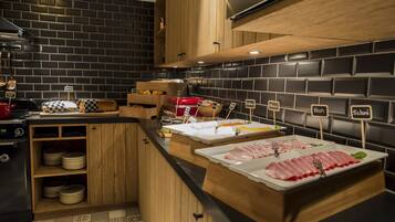 A kitchen with a black brick backsplash, wooden cabinets, and a counter displaying various food items.