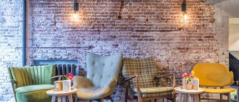 A cozy seating area with a brick wall, a radiator, and two pendant lights.
