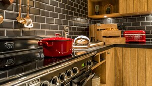 A kitchen with a black tiled backsplash, wooden cabinets, and stainless steel appliances including a red pot and a toaster.