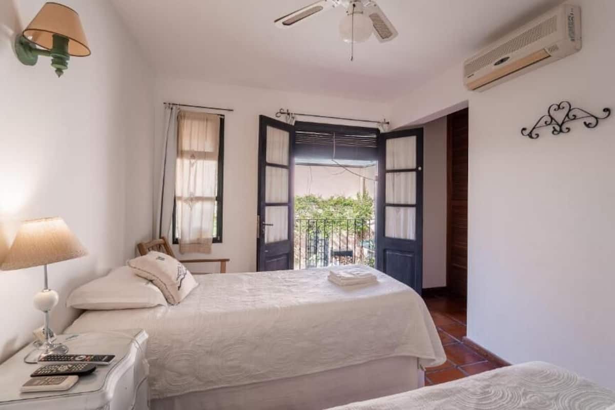 A bedroom with a bed, bedside table, lamp, and an open door leading to a balcony.
