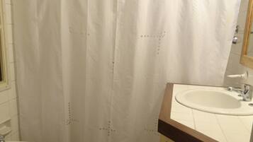 Een badkamer met douchegordijn, wastafel, toilet en handdoekhouder.