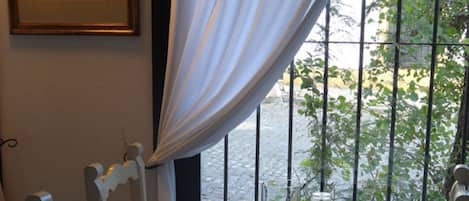 Una mesa de comedor dispuesta con platos, tazas y una jarra de vidrio, ubicada cerca de una ventana con vistas al exterior.