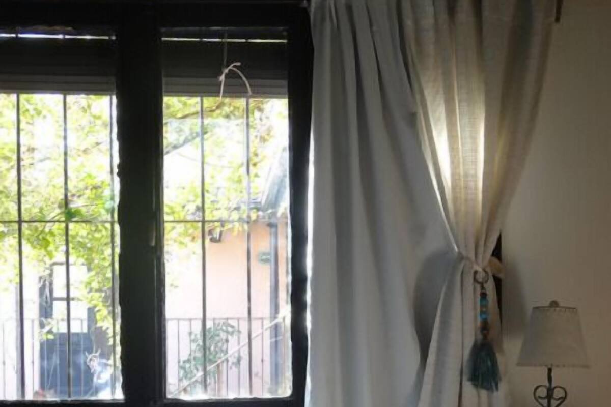 A bedroom with a bed, a nightstand, a lamp, and a window with curtains.