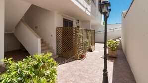 A residential building with a staircase leading to an upper floor, a balcony, and a tiled courtyard with potted plants. - L'Agrumeto (Diso)