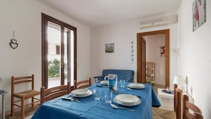 A dining area with a blue tablecloth, wooden chairs, and a blue patterned sofa. - L'Agrumeto (Diso)