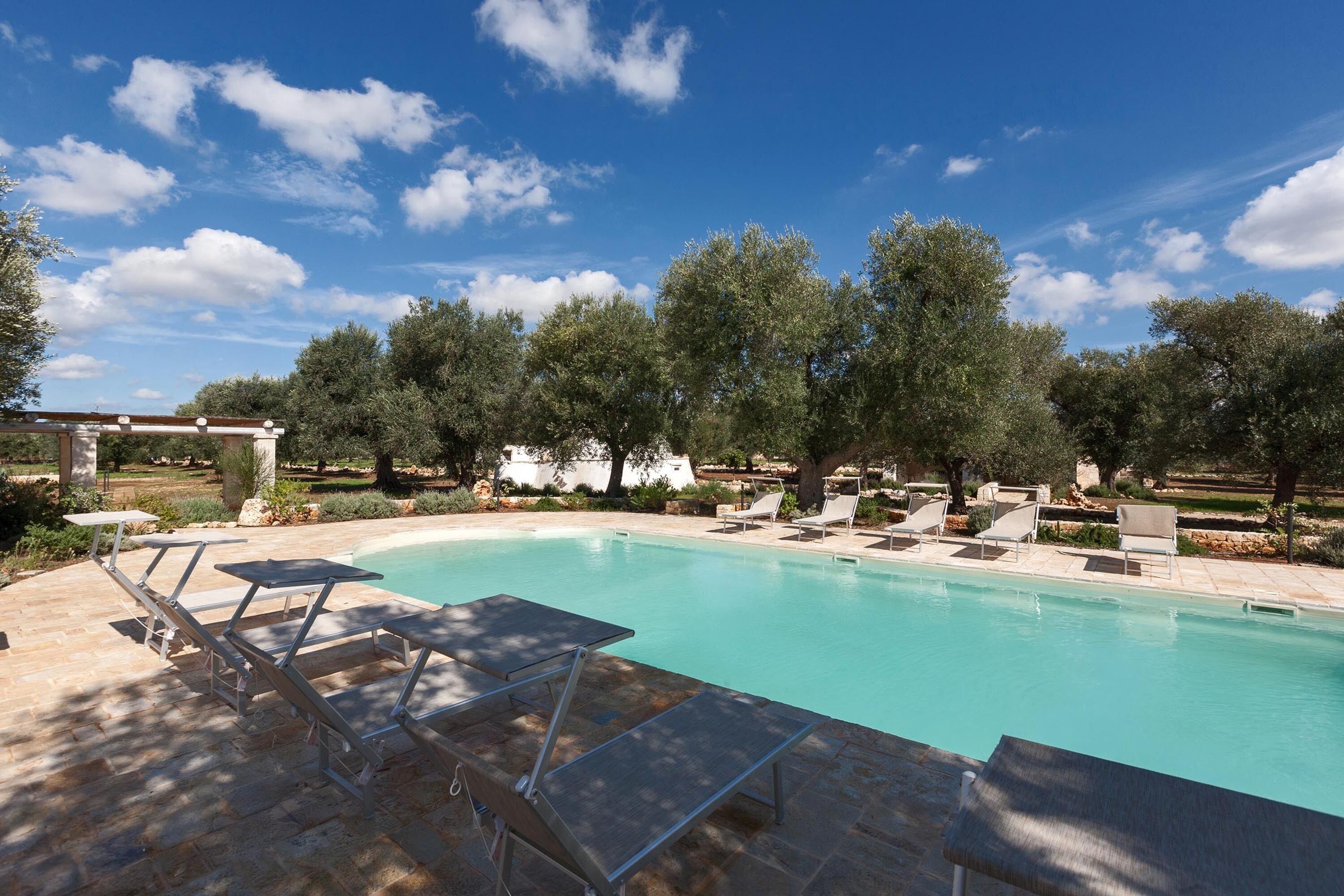 A swimming pool with lounge chairs and a pergola.