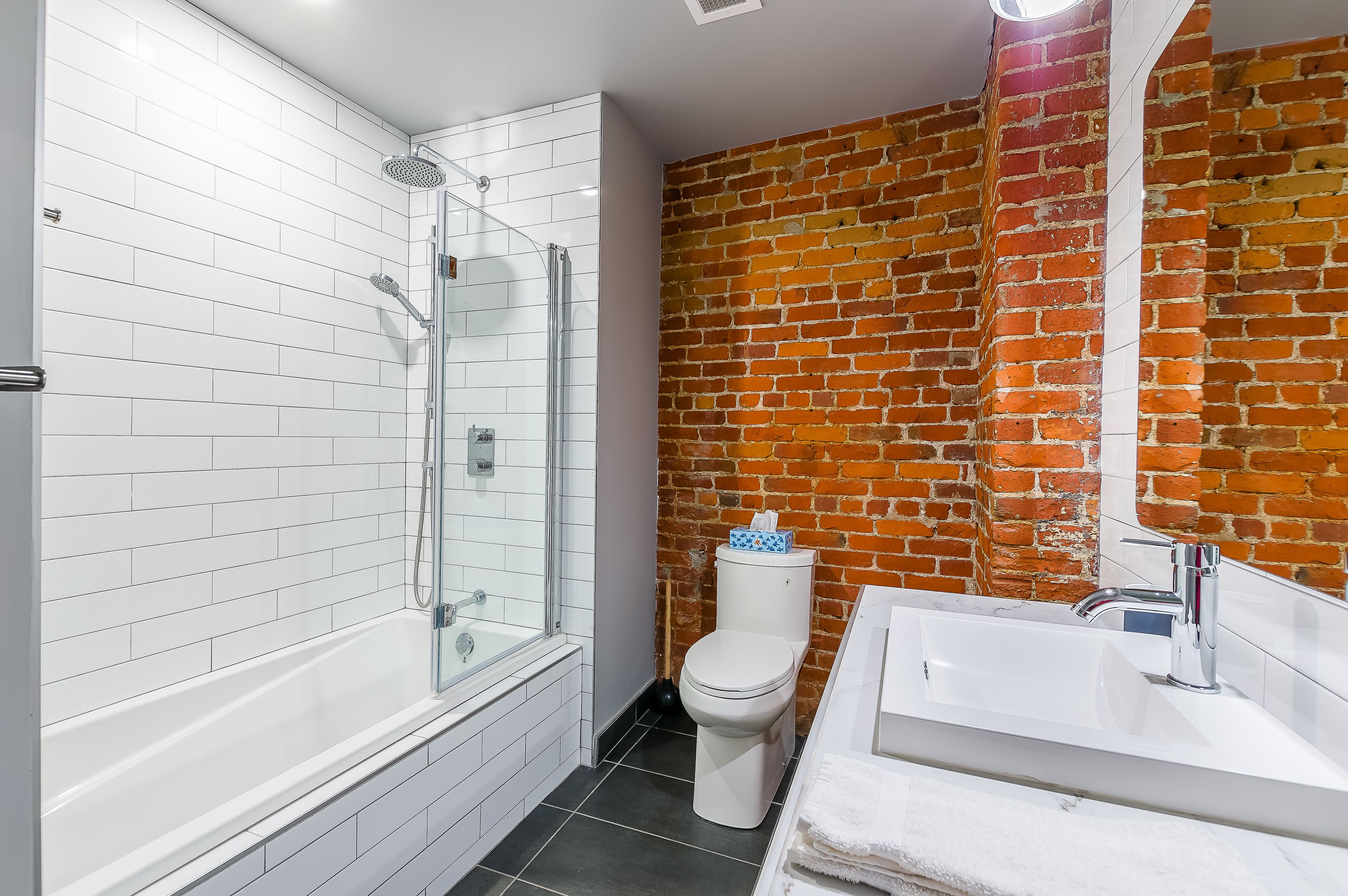 Un baño con ducha de vidrio, inodoro blanco y lavabo con espejo.