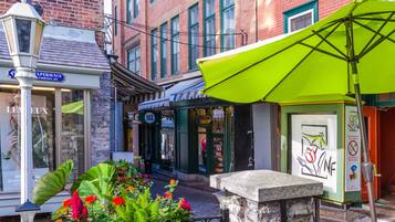 A street with a green umbrella, a flower bed, and a building with a sign that says "Experience".
