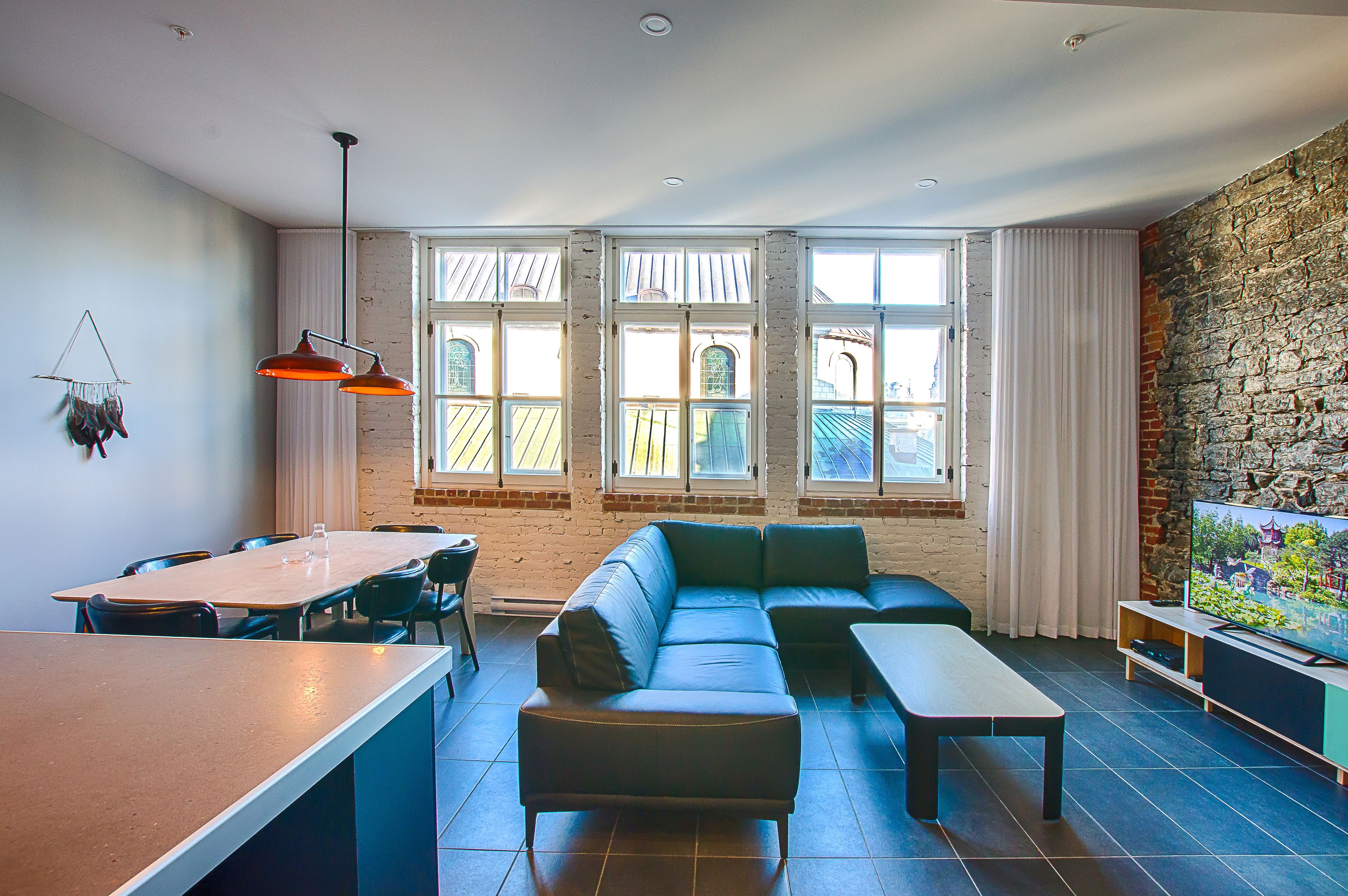 A modern living room with a sectional sofa, a dining table with chairs, and a television on a stand.